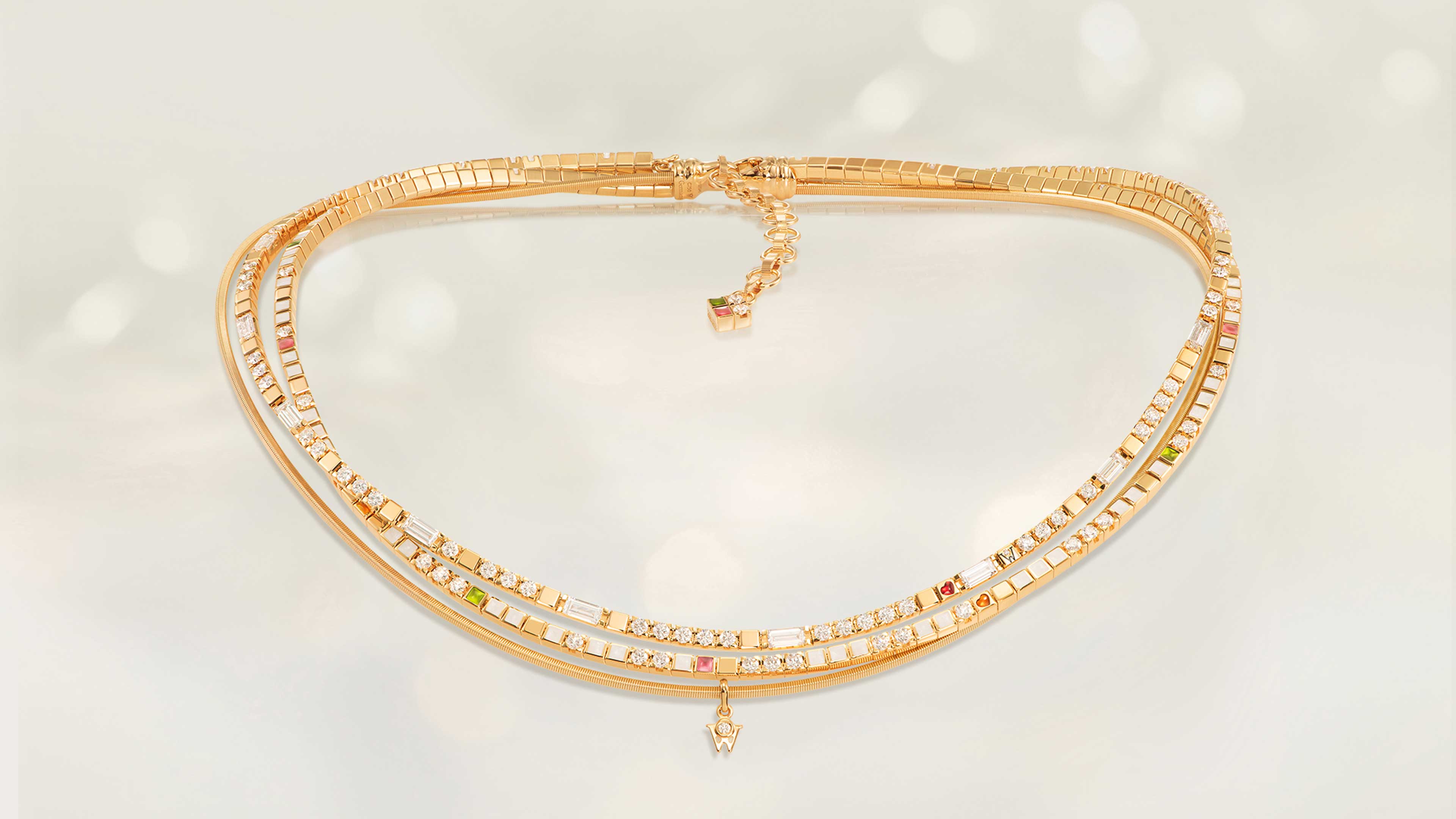 Das Collier POWER IN WHITE edel aus 18 Karat Gelbgold verbindet Perlmuttweiß, Grün, Orange, Rosé, feinen Sternenstaub, Brillant-Baguettestrang und ein Herz. Collier auf hellem Hintergrund.