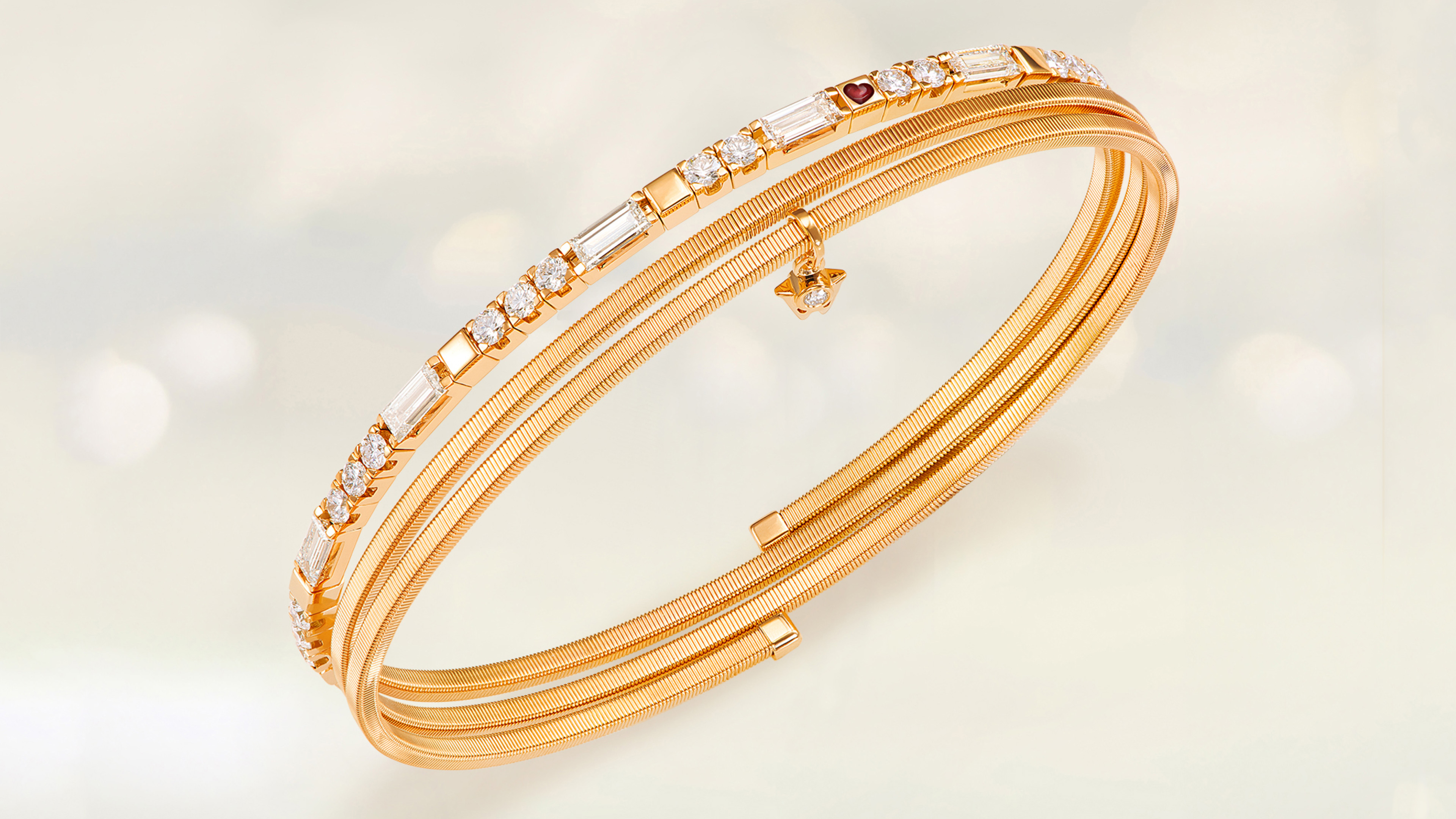 Das Armband UMARME MICH Baguette-Zauber aus 18-karätigem federnden Gelbgold und funkelnden Baguette-Diamanten auf grauem Mood Hintergrund.