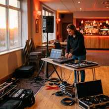 A mobile DJ setting up a laptop and PA before a show