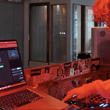 A KJ running a karaoke night from a laptop next to a DJ mixer in a bar