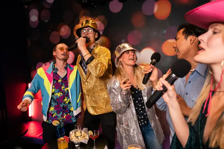 Group of people in a karaoke room with microphones singing using Singa Karaoke