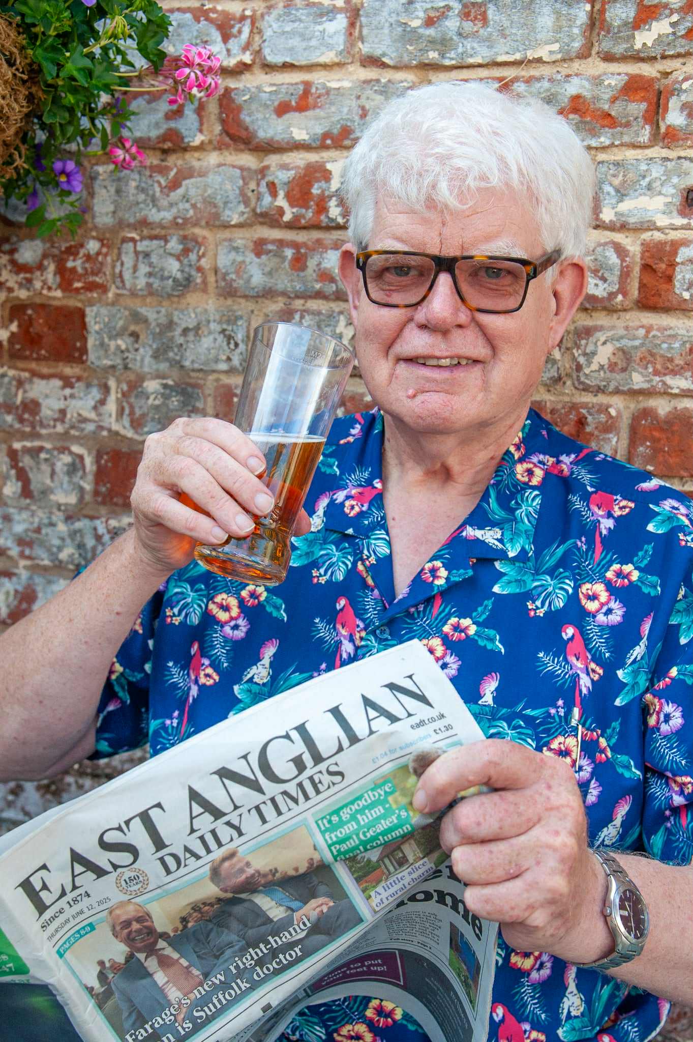 Paul Geater holding a beer aloft with a newspaper