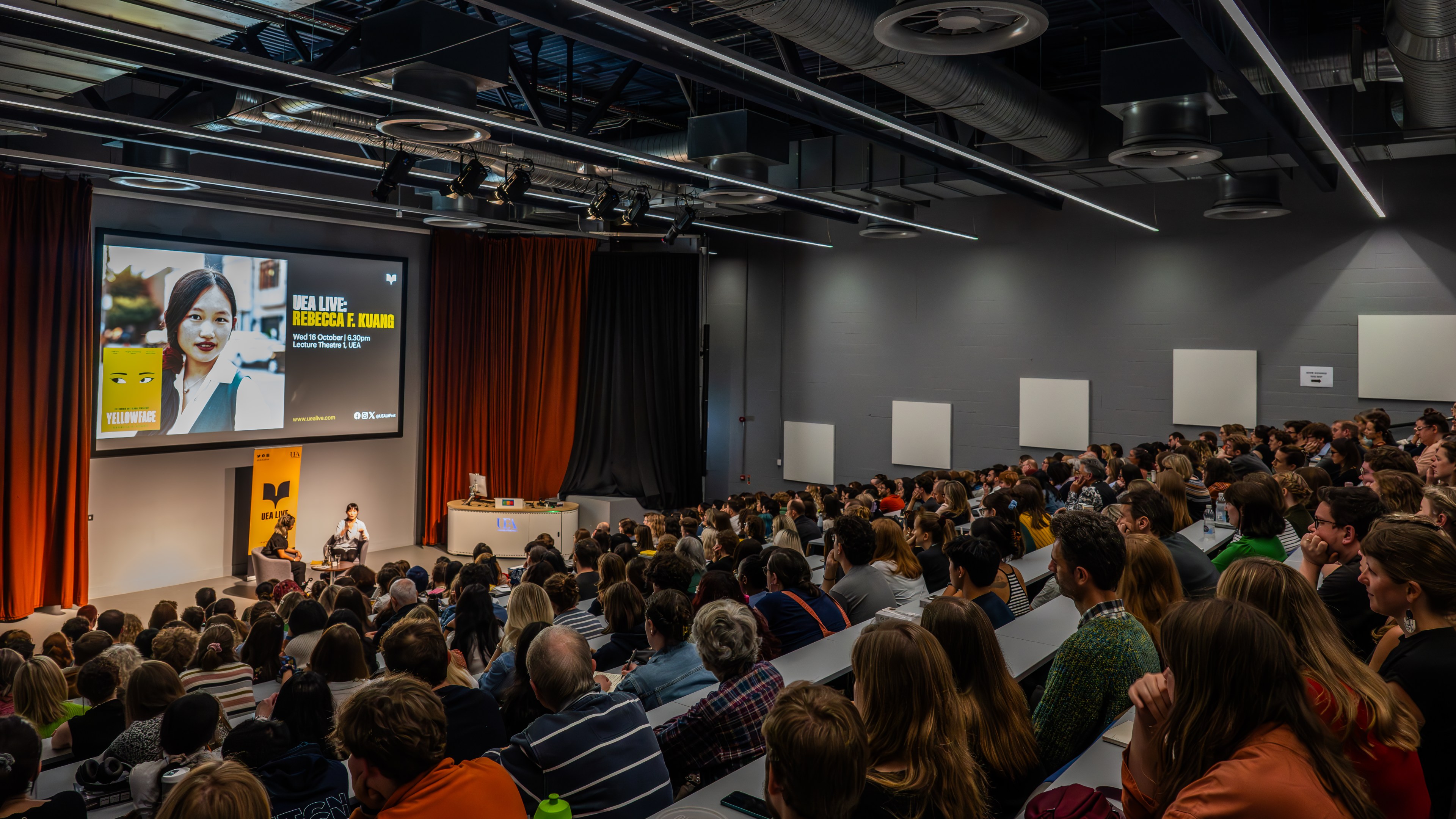A lecture theatre of people watching an author speak.