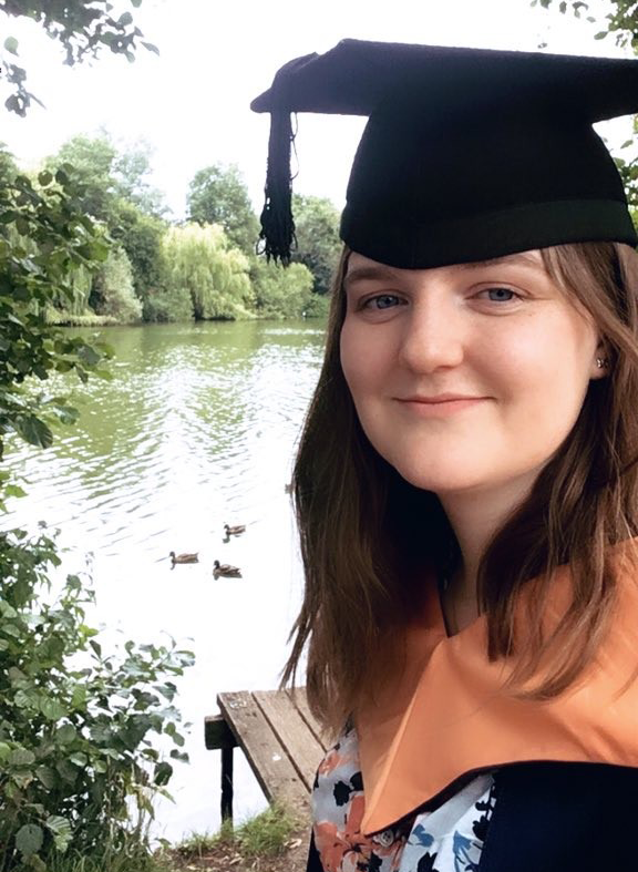 Natalie Froome standing in front of UEA Broad in Graduation gown and cap