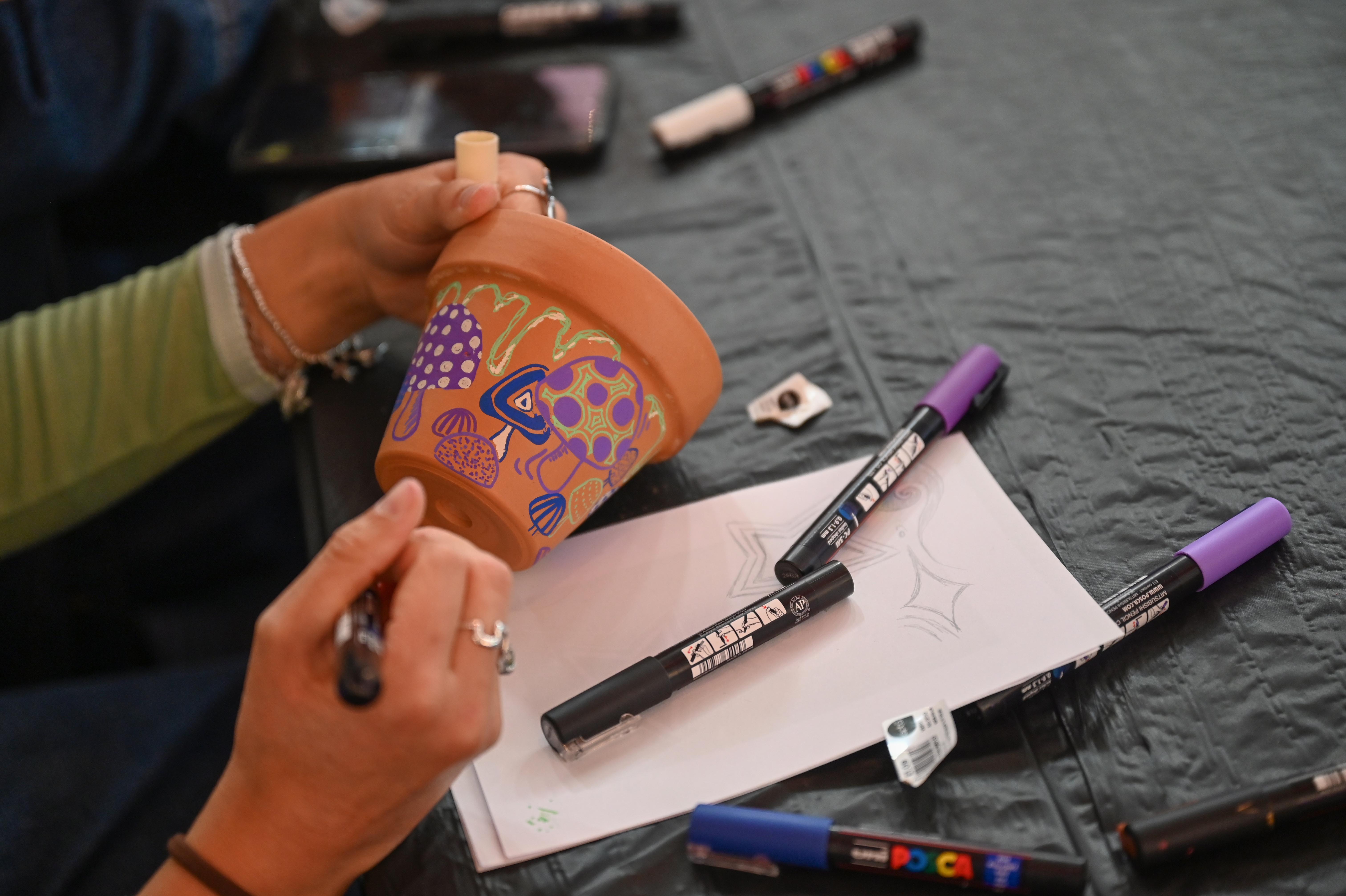 A student painting a plant pot during Welcome Week