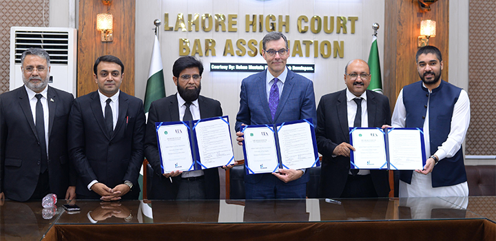 A group of six men in formal attire stand holding documents in front of a sign reading "Lahore High Court Bar Association"