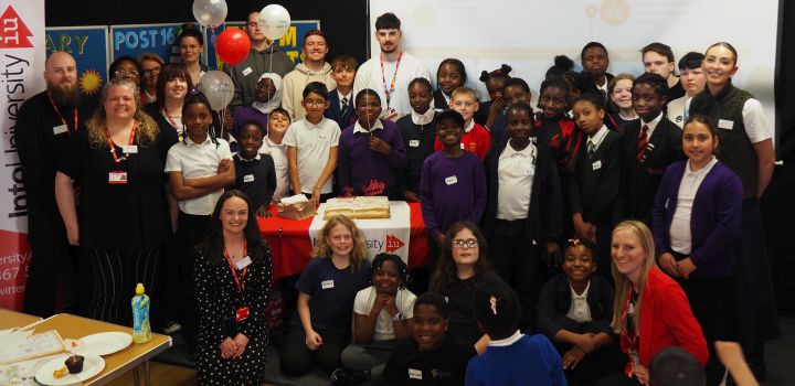 A large group of diverse schoolchildren and staff celebrate together at an IntoUniversity event in Norwich.