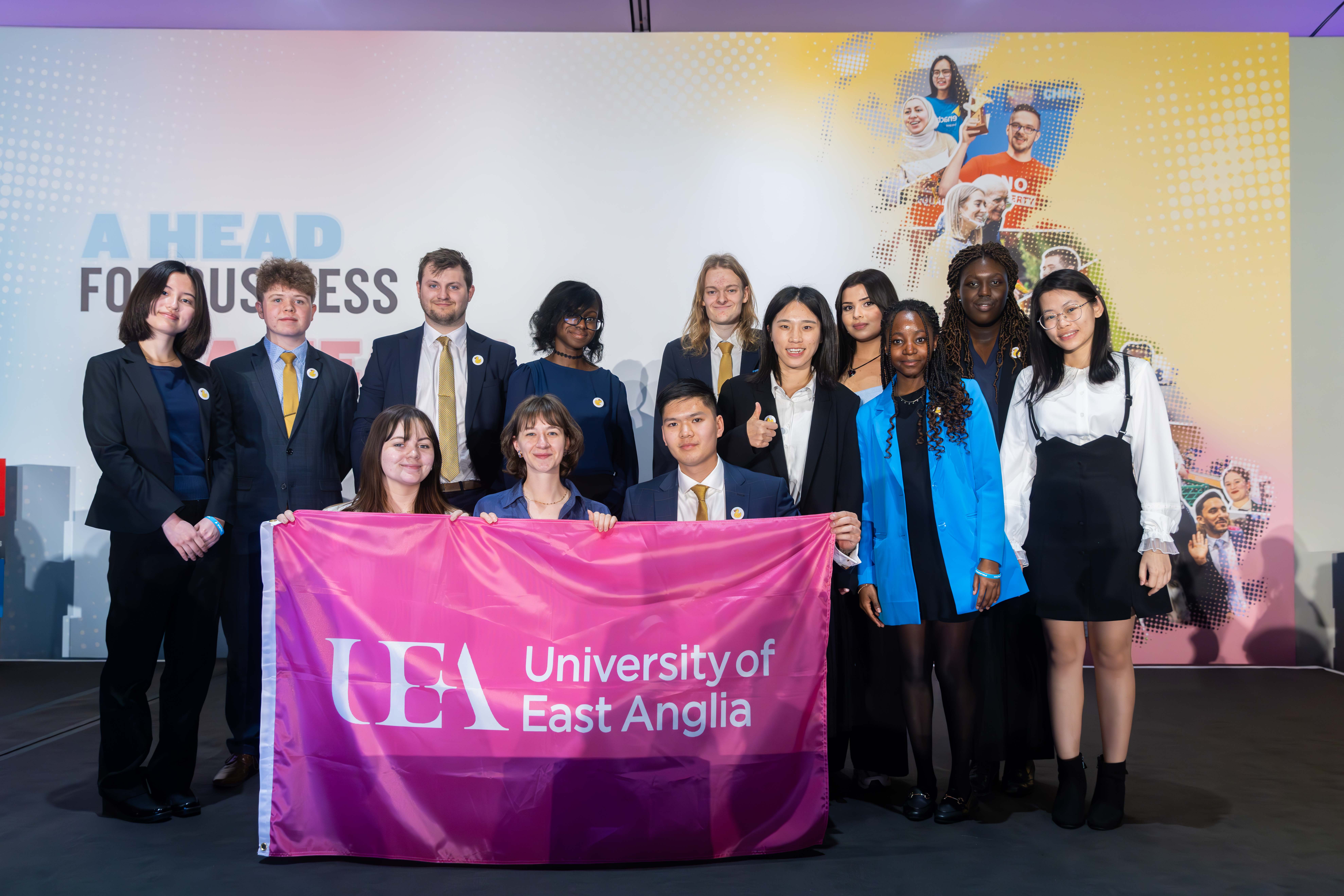 Enactus UEA team at the Enactus National Finals. Top row L-R: Tsukine Teranishi, Sam Newman, Ben Bishop, Lily Asenso, Zac Steventon-Barnes, Hongli Nian, Sabreena Khan, Ruvimbo Mazarura, Abioseh Kamara, An Ha. Bottom row L-R holding the flag: Katherine O’Connor; Natalie Chabot; Conrad Yip