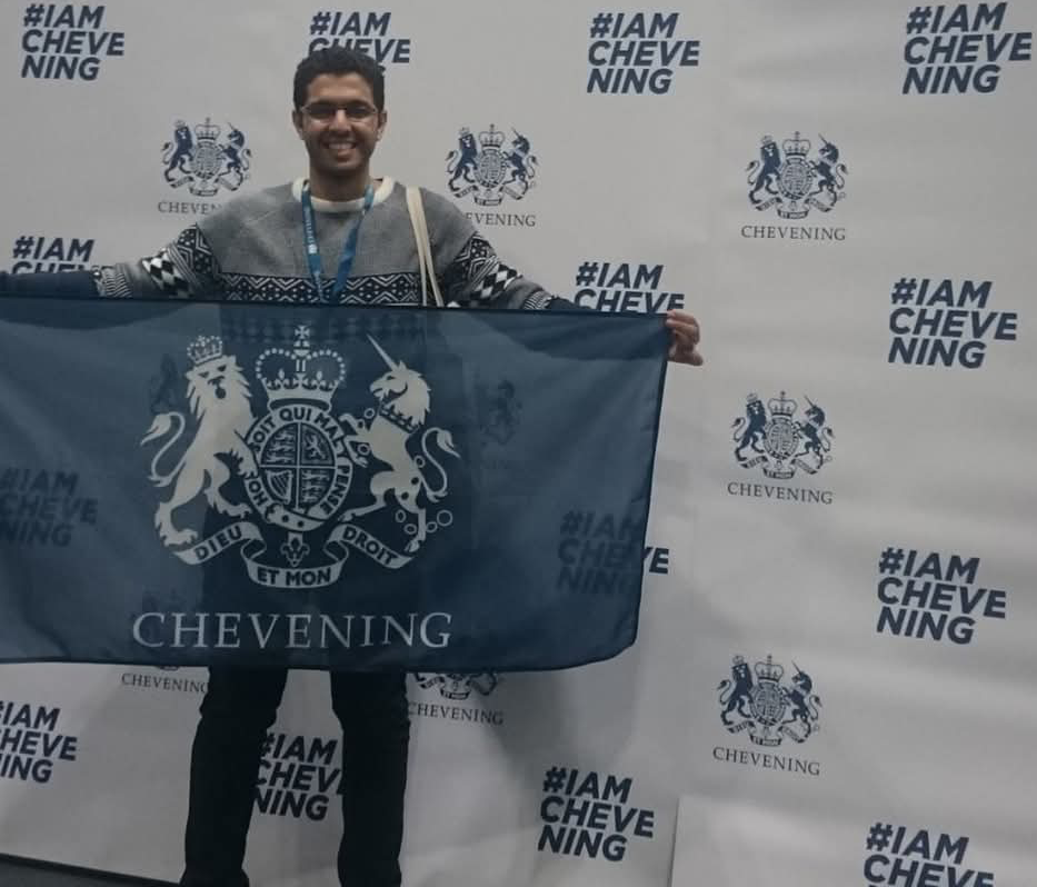 Picture of Moustafa Kamal holding Chevening Scholar flag