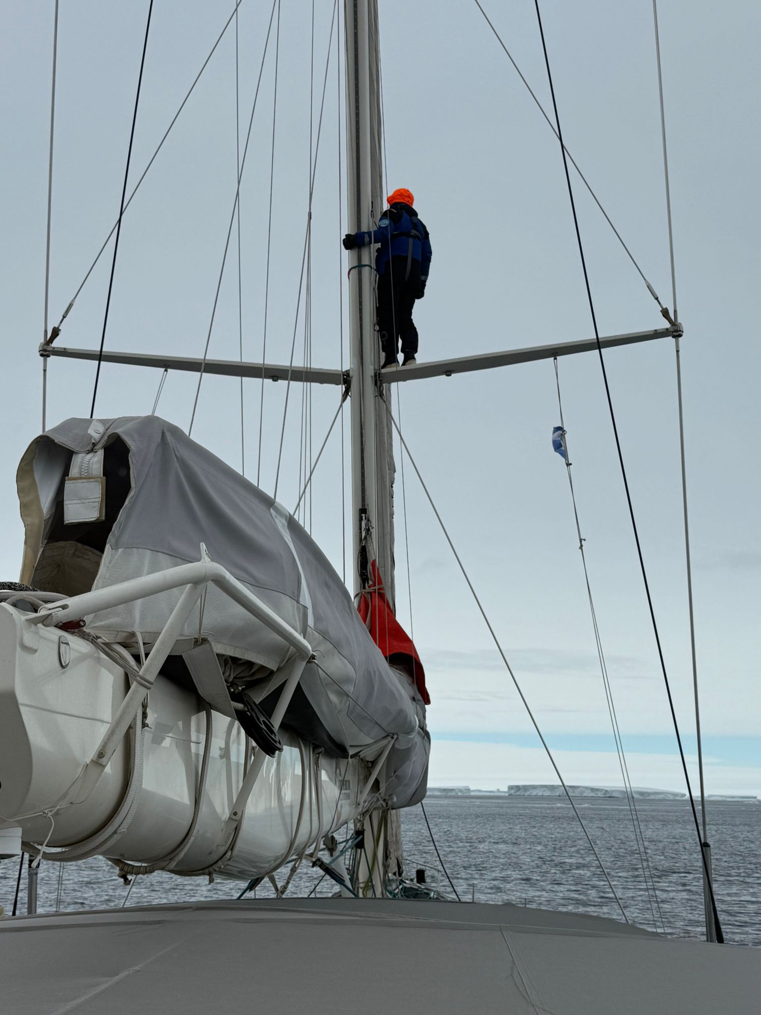 Marin Moreau, sailor on Malizia Explorer, standing on the mast spreader for a better view.