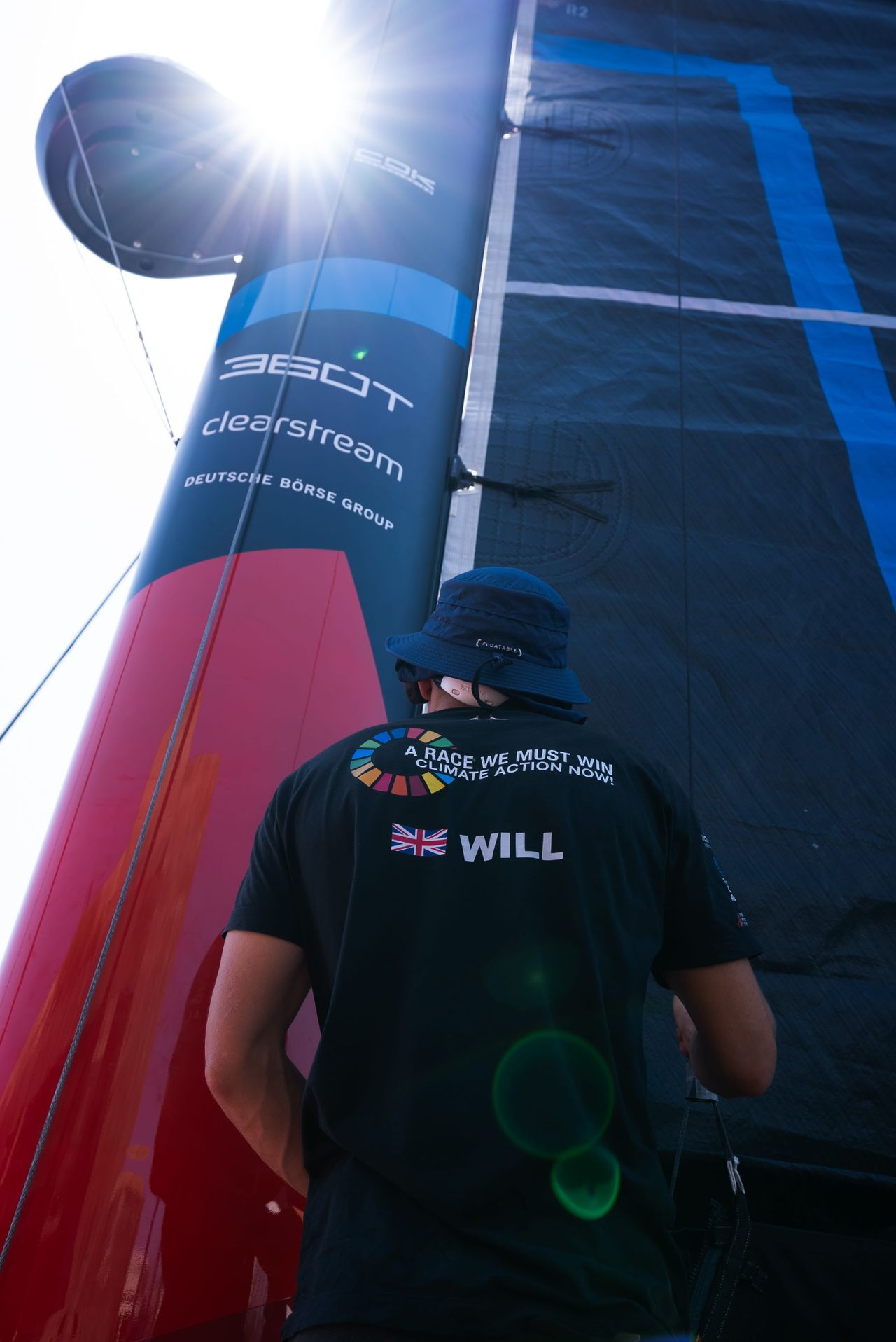 Co-skipper Will Harris standing next to the 27 m mast of Malizia 4