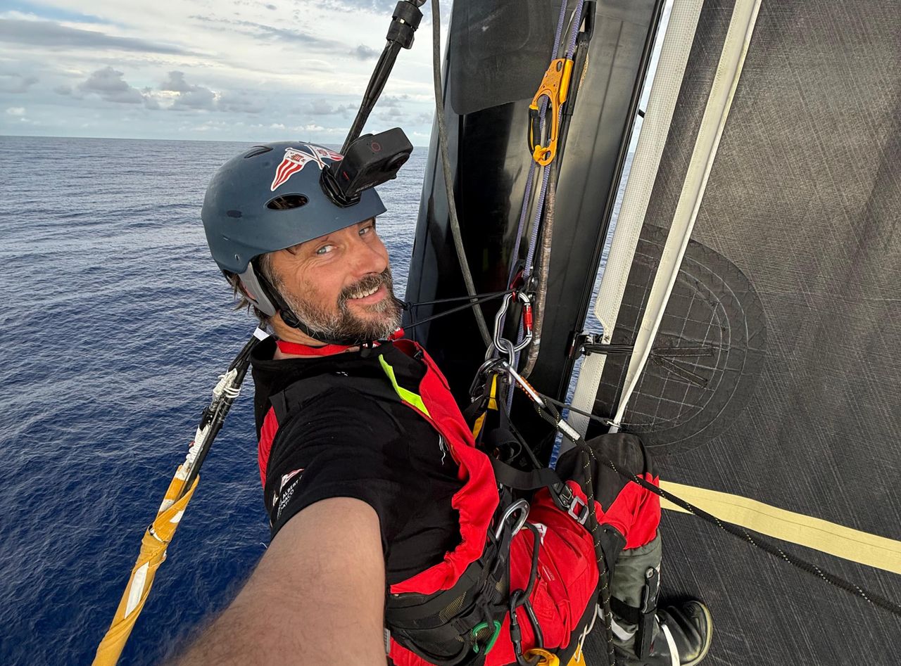 A smiling Boris Herrmann at the top of his mast after a successful arbalète repair in large parts thanks to the coordinated effort of his shore team to find a practical solution