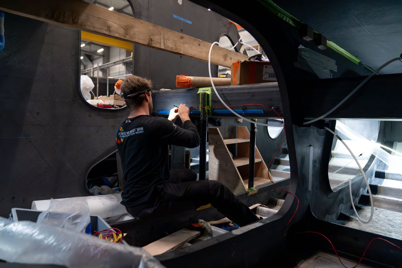 Connor Banks installing the electronics on Team Malizia’s new IMOCA as electrification work accelerates with six weeks to go