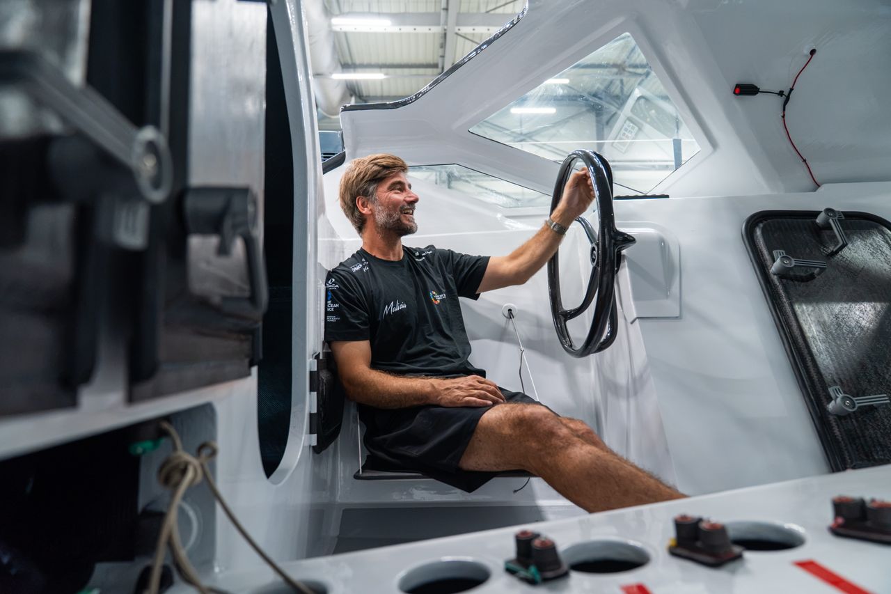 Boris Herrmann sitting in the cockpit of his new IMOCA race yacht which features steering wheels instead of a tiller