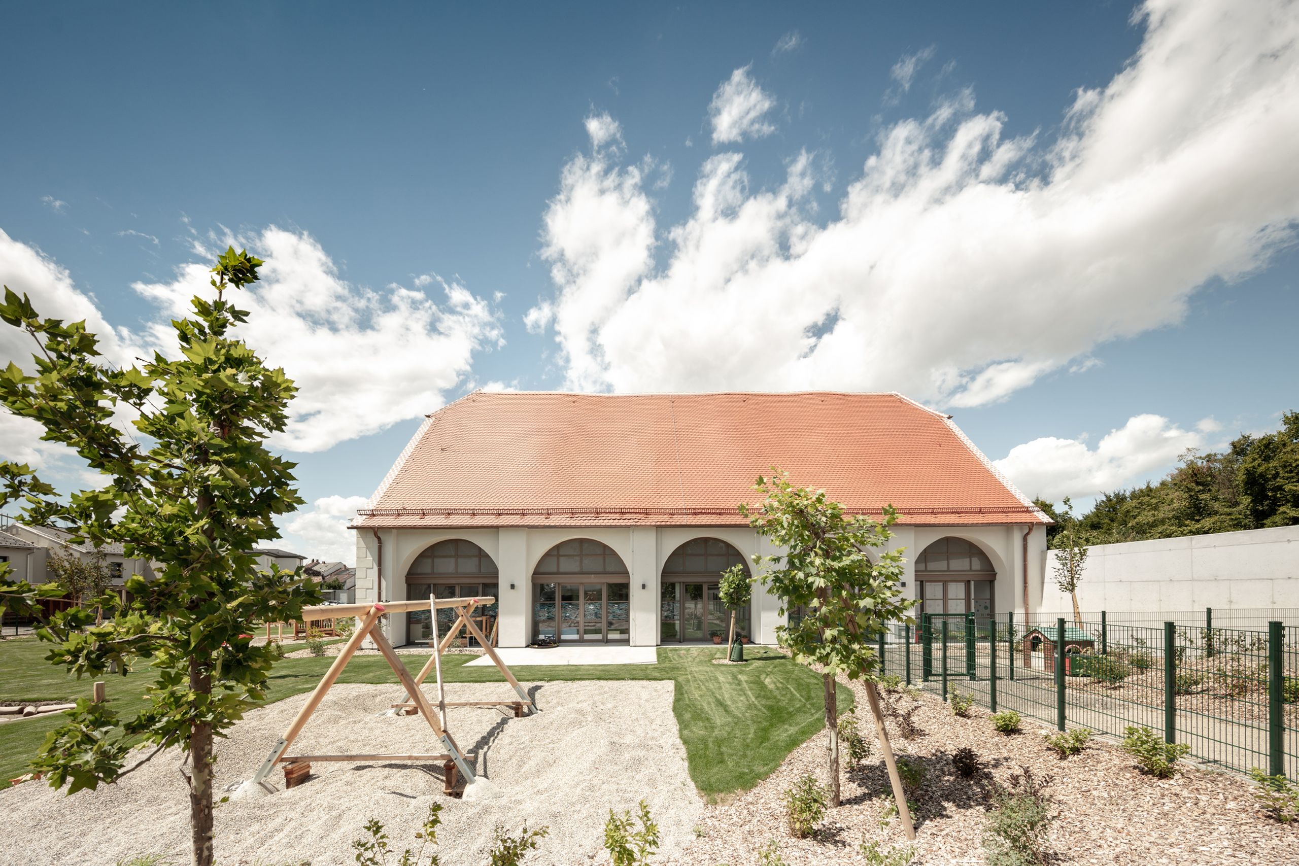 Außenansicht des umgebauten Kindergartens Wullersdorf mit Spielbereich und historischem Gebäudebestand