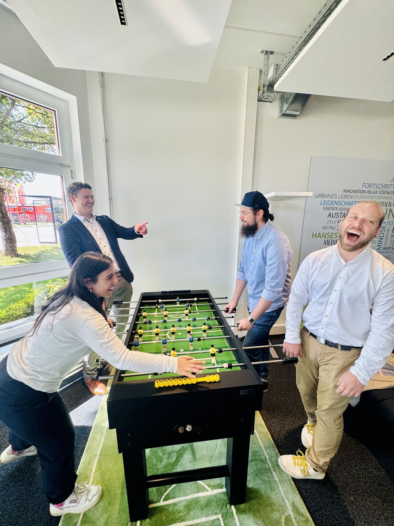 Kolleg:innen beim Tischkicker spielen