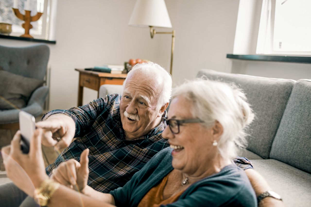 Fröhliches Rentner Ehepaar sitzt auf der couch