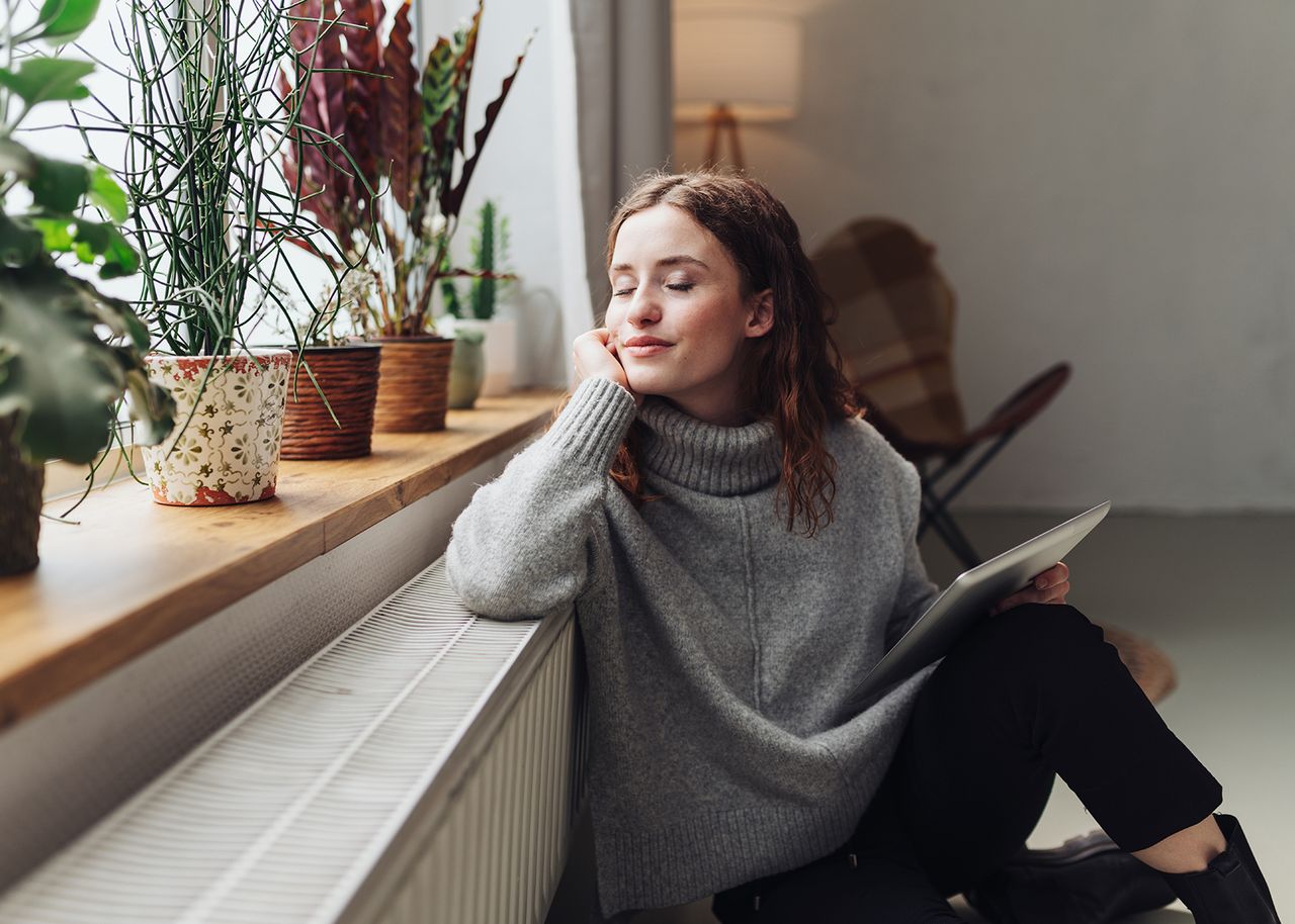 Frau sitzt an Heizung