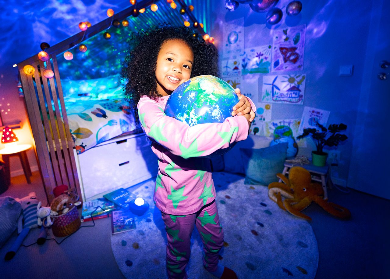 Strom: Mädchen umarmt einen Globus im beleuchteten Kinderzimmer