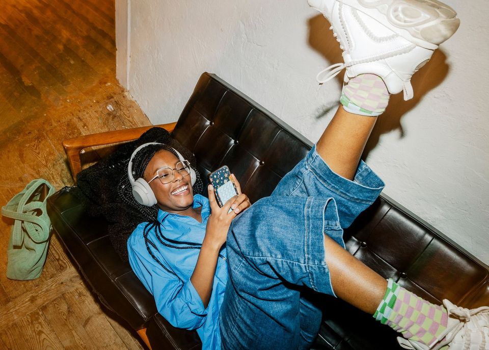 Frau liegt auf Sofa mit Handy in den Händen