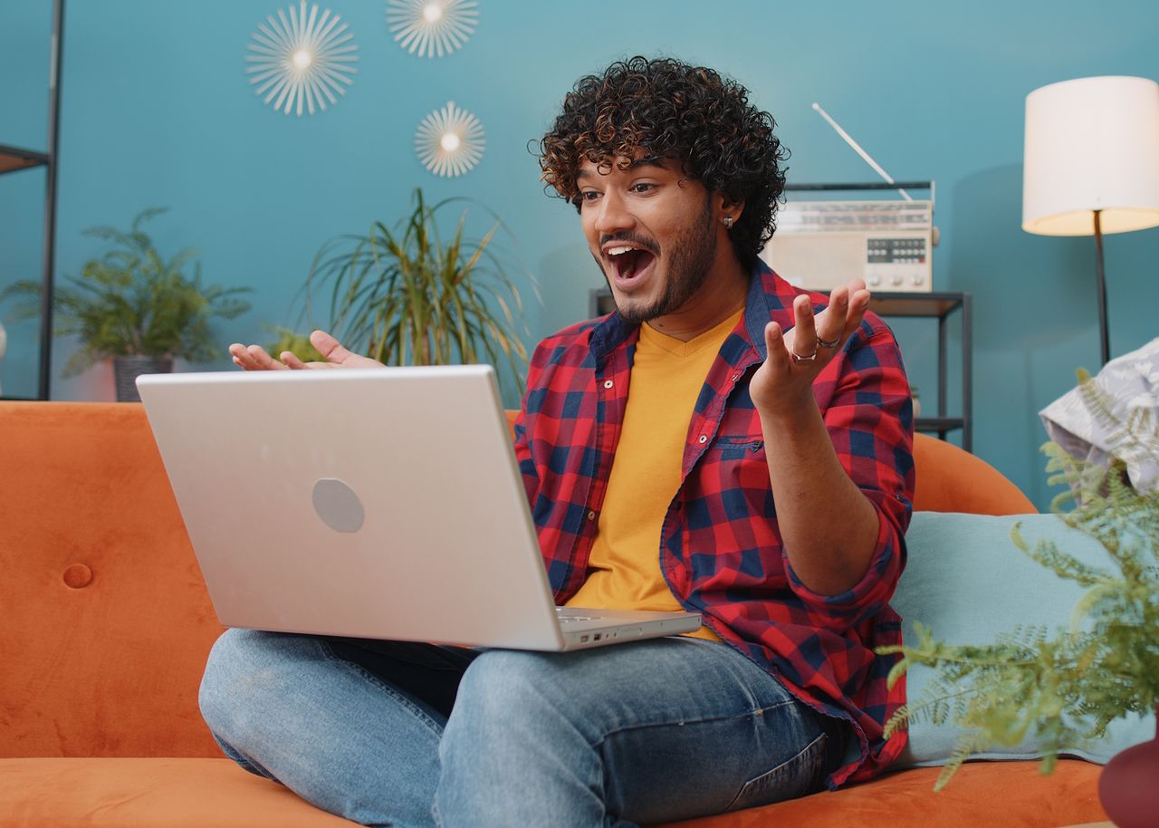 Mann sitzt auf Sofa mit Laptop