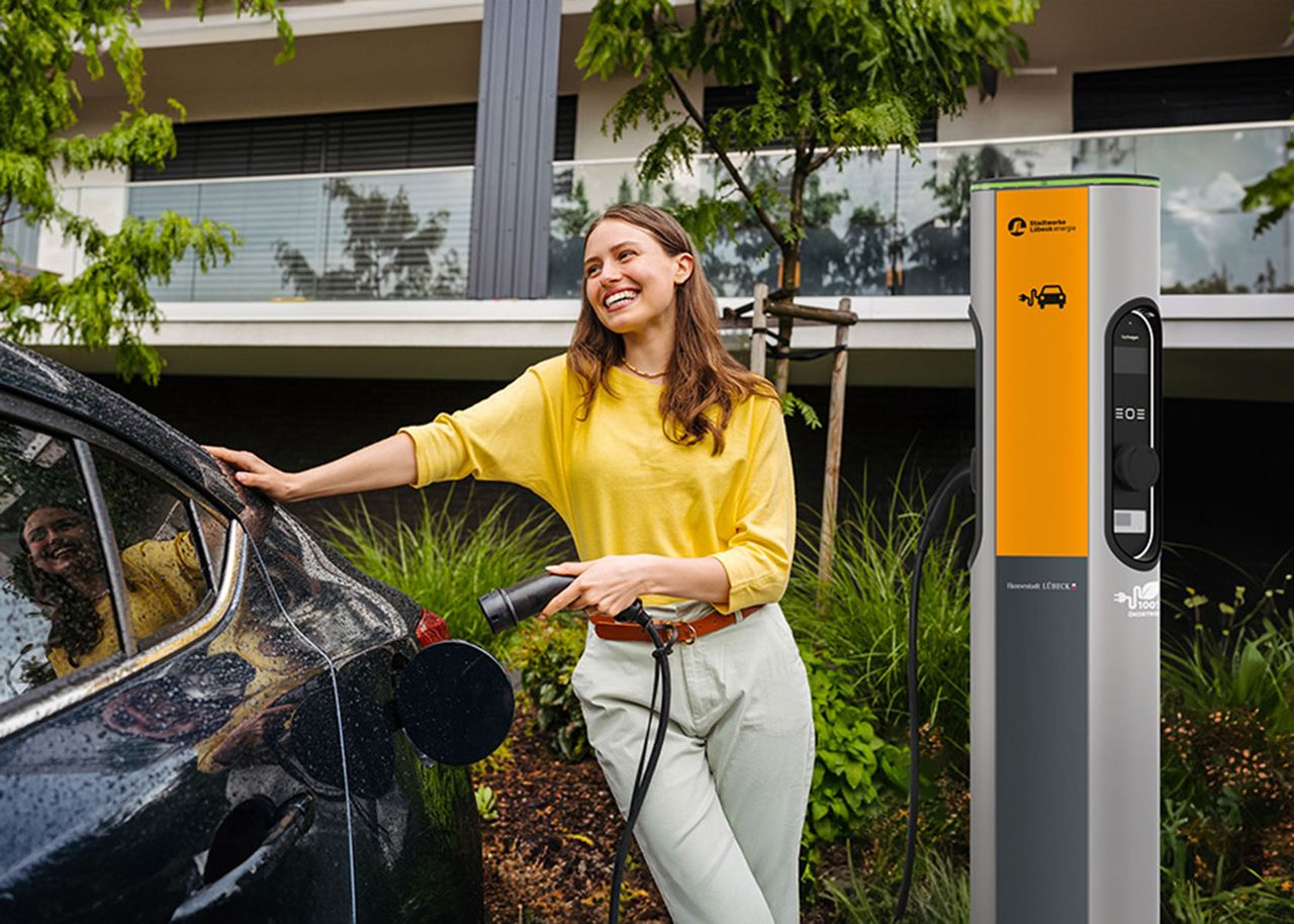 Frau steht neben einer Ladesäule der SWL Energie und lädt ihr Auto