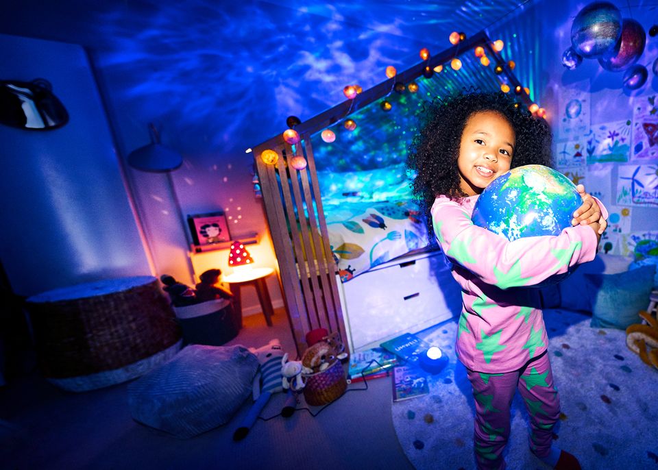 Strom: Mädchen umarmt einen Globus im beleuchteten Kinderzimmer