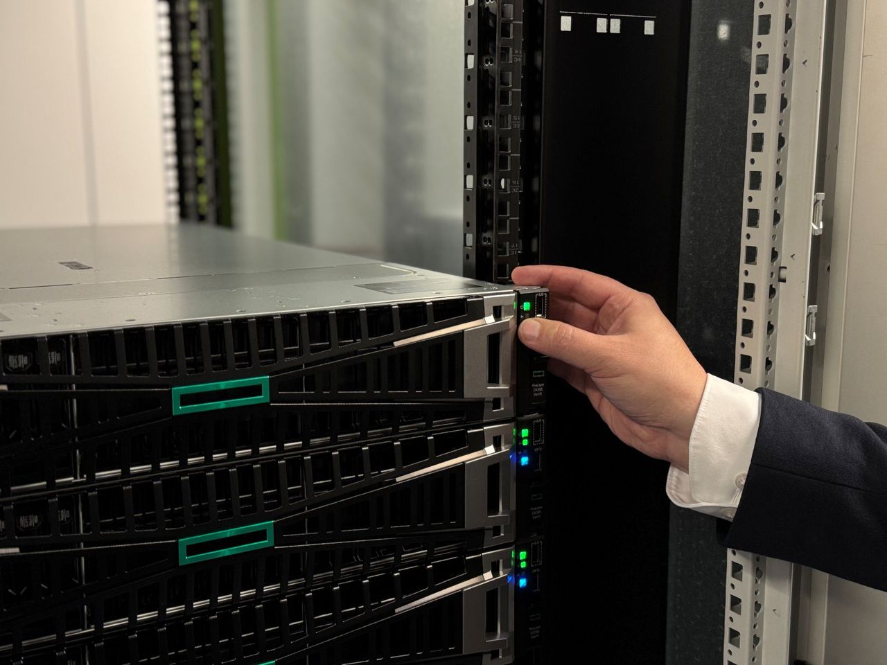 Eine Hand richtet ein Serverrack in einem Rechenzentrum aus, während die Statusleuchten grün und blau leuchten.