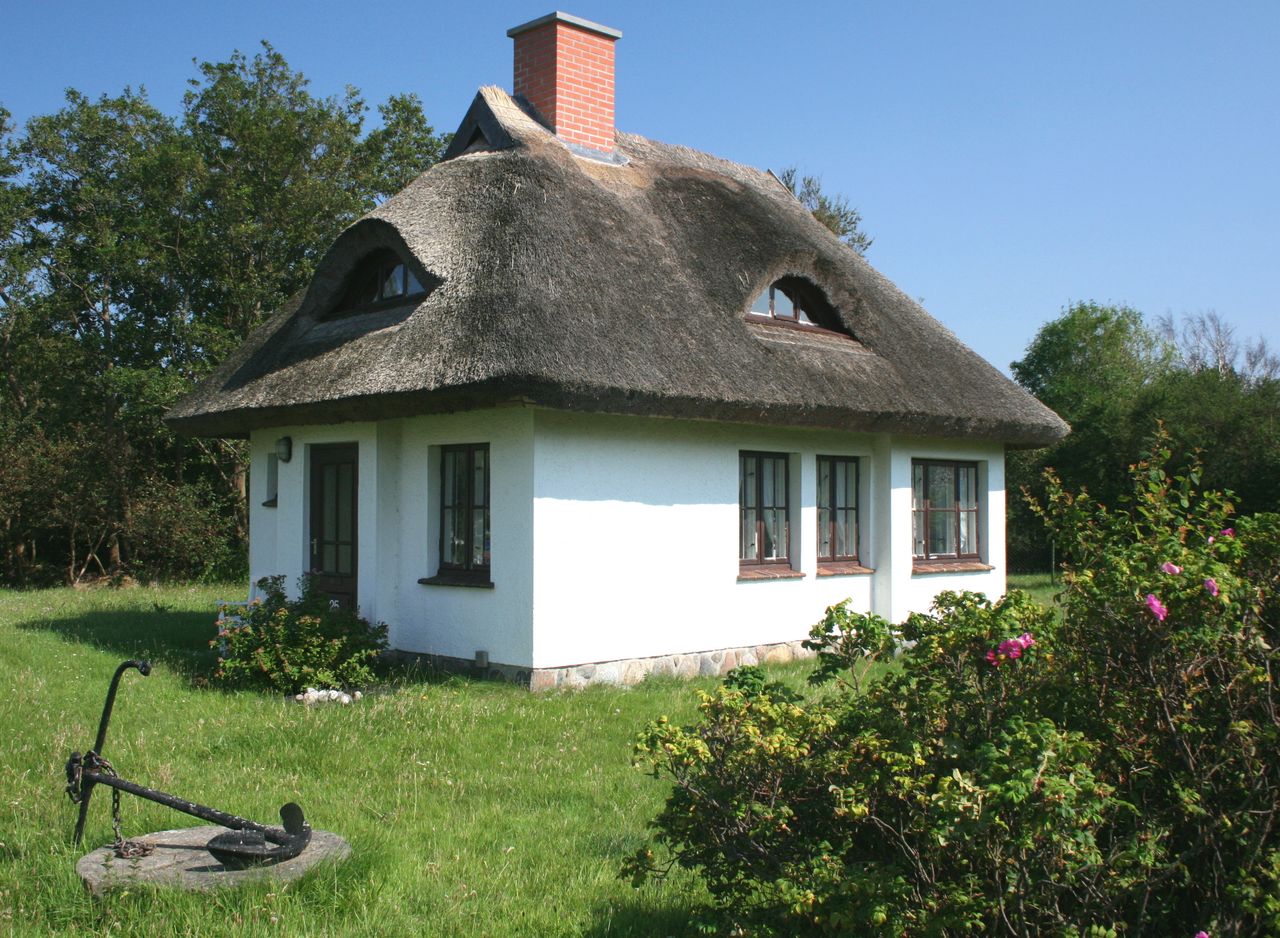 Ein altes Reetdachhaus steht in mitten eines grünen Gartens