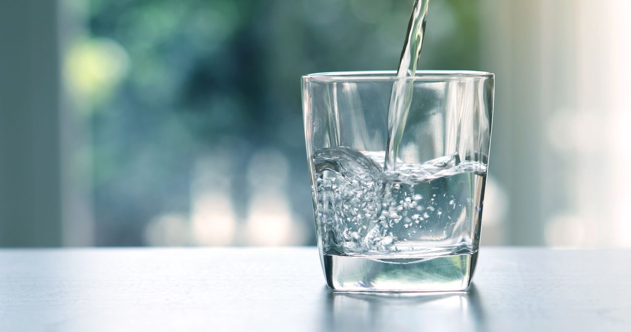 Wasser wird in ein Glas auf einem Tisch geschüttet