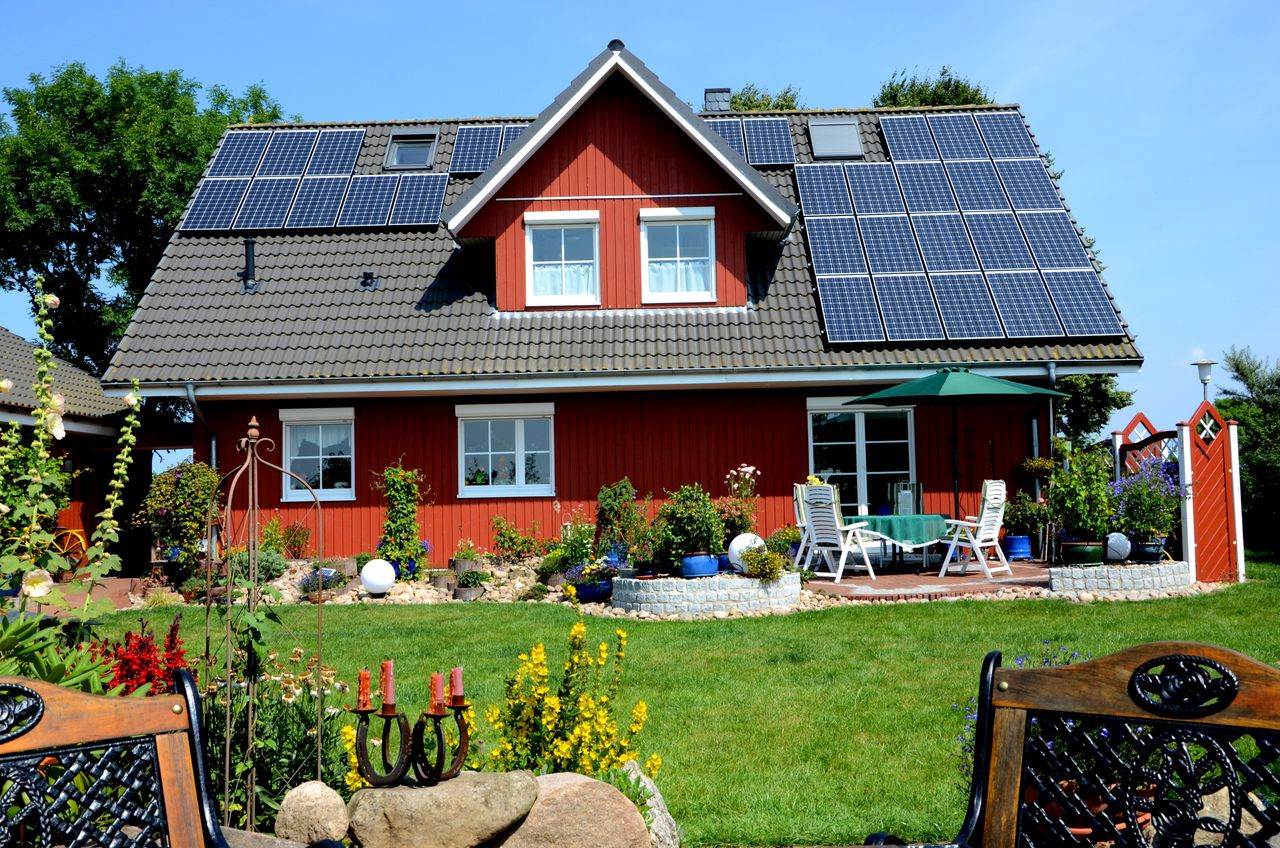 Haus mit roter Fassade und PV-Anlagen auf dem Dach