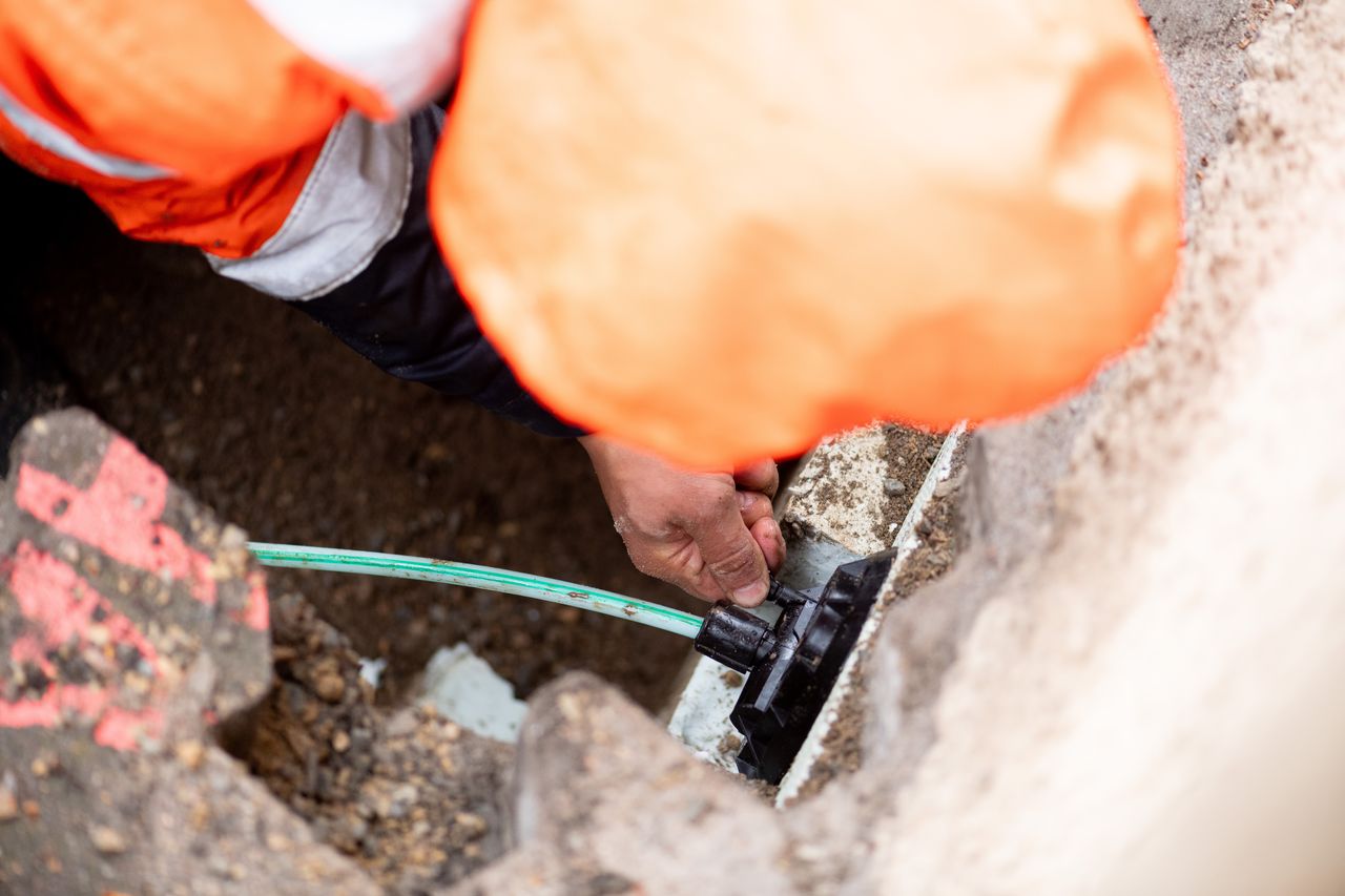 male worker installing fiber cable on house