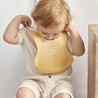 Baby Bib in powder yellow with a big spill pocket - BabyBjörn