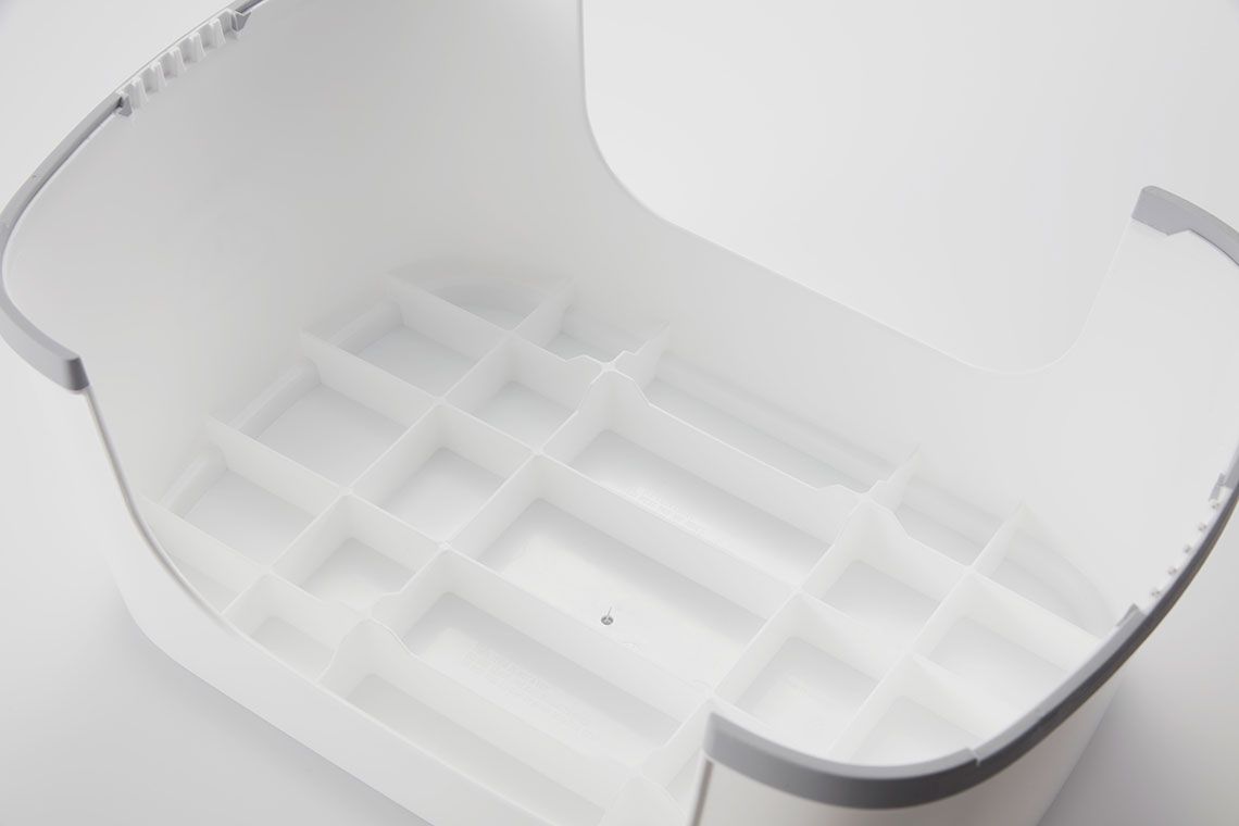 White plastic storage container with a grid-like interior and curved edges, placed on a light surface.