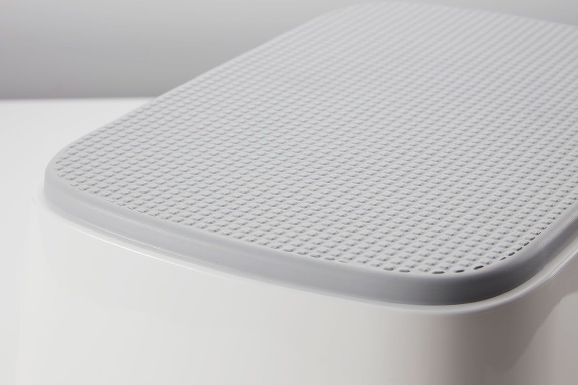 Close-up of a white textured surface with a grid pattern on a rounded rectangular object against a light gray background.