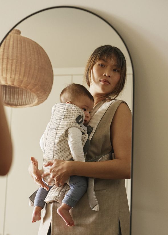 Mum looking in the mirrow with baby in a Baby Carrier Mini in cream 3D mesh - BabyBjörn