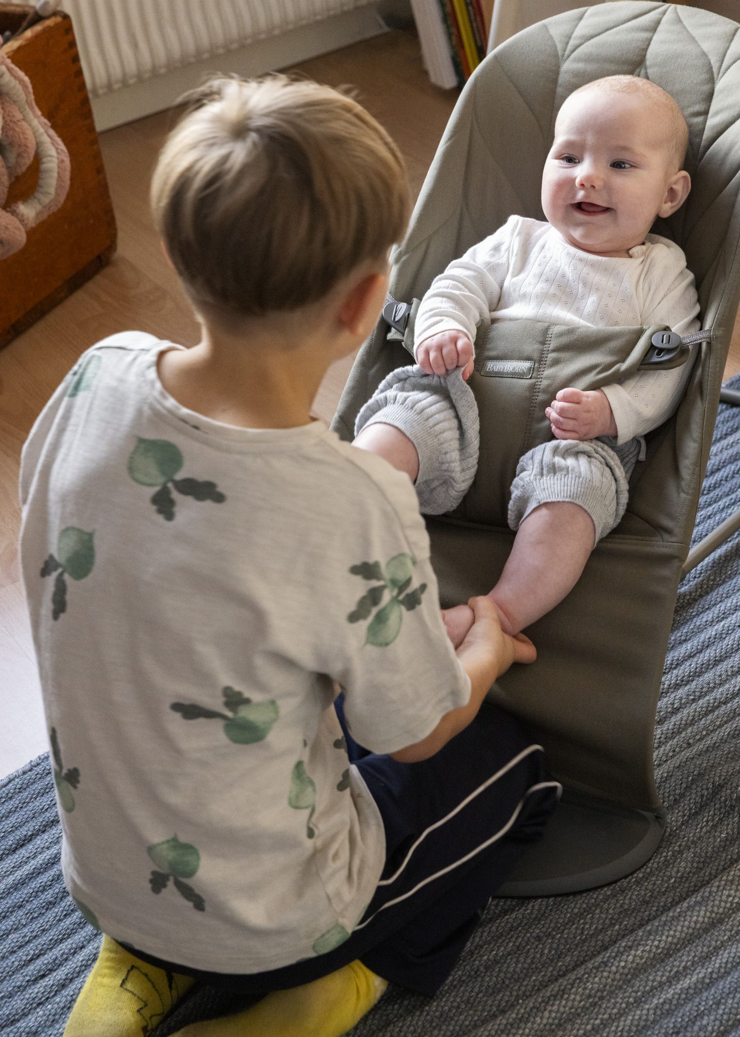 Newborn diaries, baby in Bouncer Bliss in dark green quilt with bigger sibling - BabyBjörn