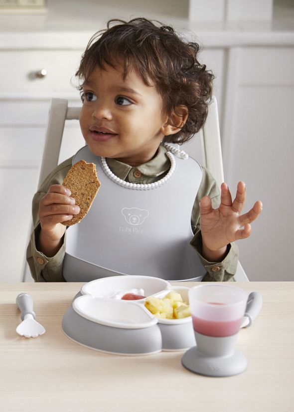 Dinnerware set in gray with baby plates, cup and cutlery and a bib with spill pocket - BabyBjörn