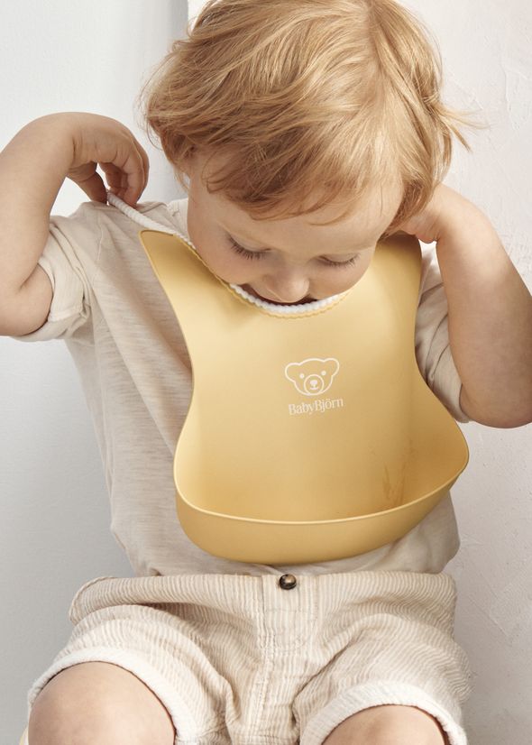 Baby Bib in powder yellow with a big spill pocket - BabyBjörn