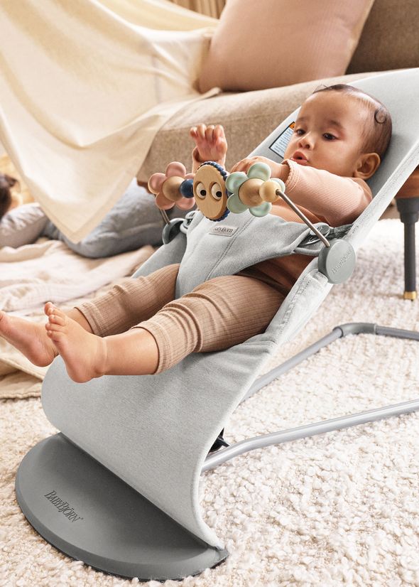 Baby in a bouncer with a toy bar Googly eyes pastels