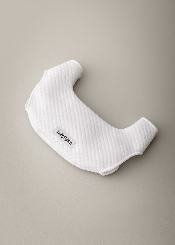 White quilted shoulder strap cover with a "Baby Björn" label, set against a neutral background.