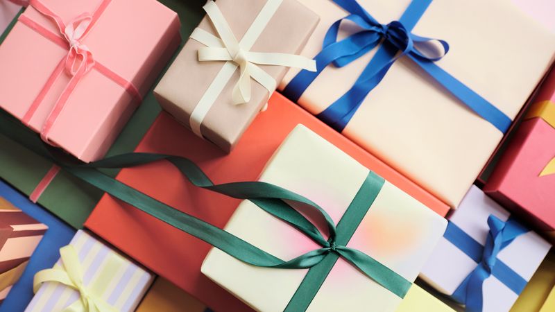 A collection of colorful gift boxes with various ribbon styles and colors, arranged closely together.