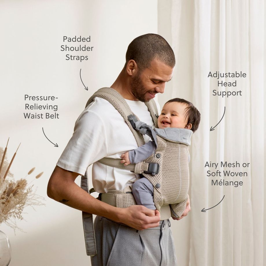 Father smiles at his laughing baby in a beige mesh front carrier with padded shoulder straps and a supportive waist belt.
