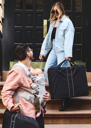 mother and father whit baby in baby carrier & travel crib