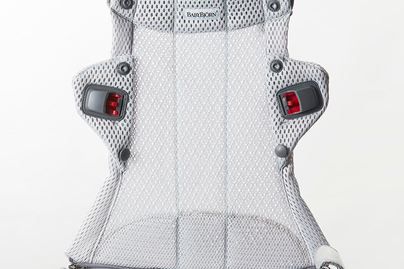 Gray mesh baby carrier with adjustable straps and red buckle accents, designed for comfort and support.