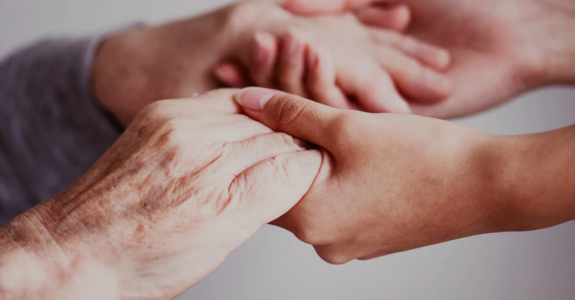 Nahaufnahme von zwei Händen – eine ältere und eine jüngere – die sich gegenseitig halten.