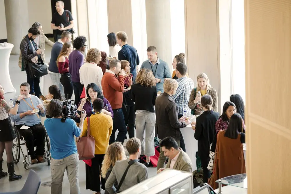 group of people standing together at tables with snacks