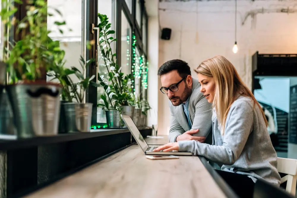 Zwei Geschäftsleute am Laptop in einem Raum im Industrie-Look