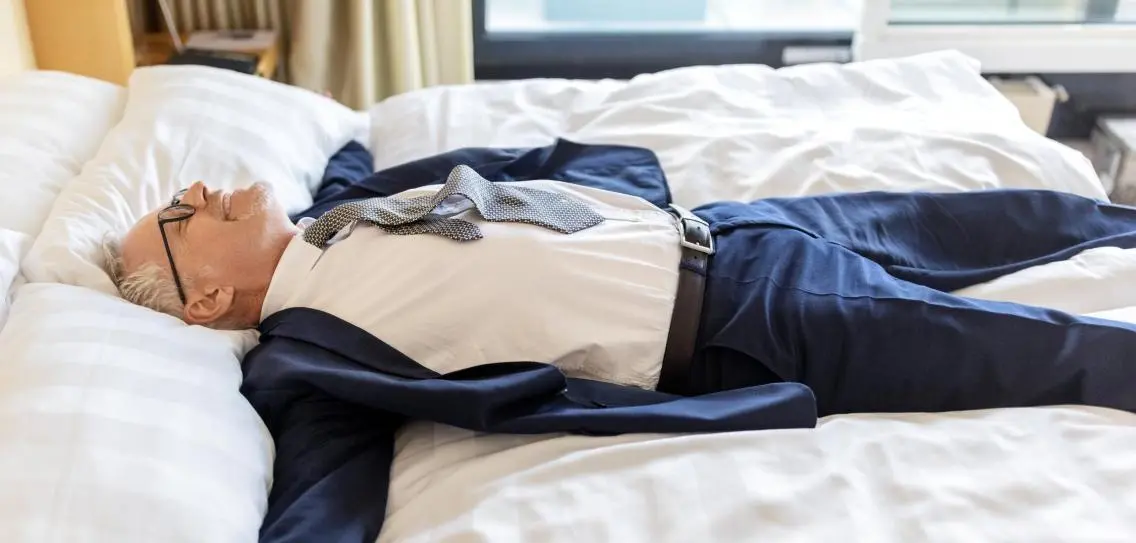 Tired Businessman Lying On Hotel Room Bed