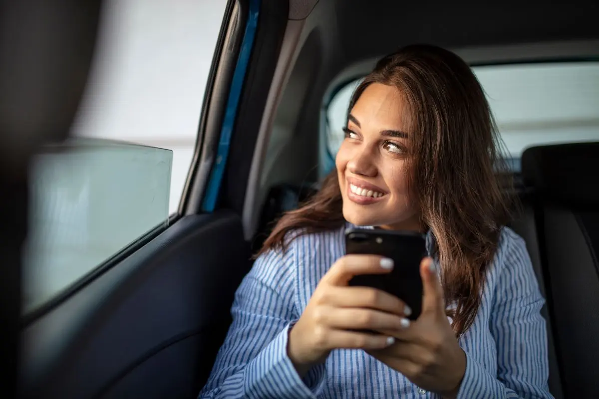 Woman Sitting In Car With Cell Phone